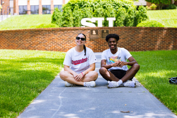 Two students in front of SU statue